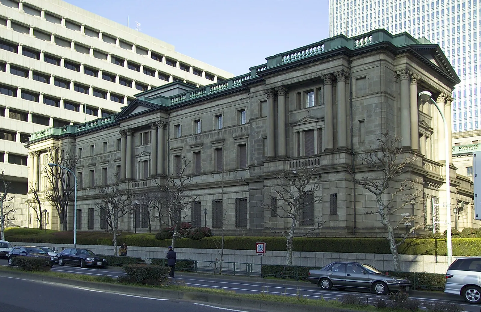 証券取引所の電光掲示板に映る株価とチャートを見つめる投資家たち